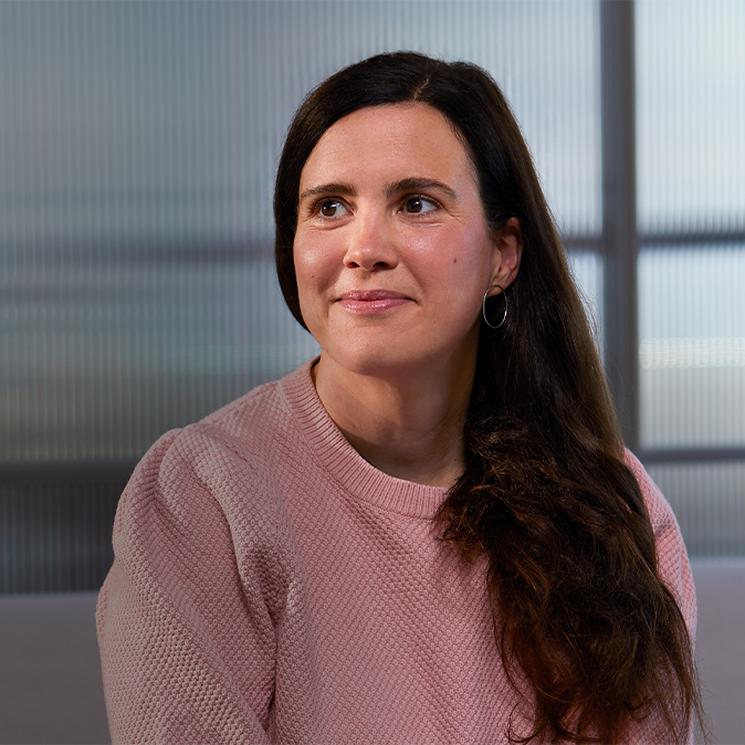 Lucie sitzt drinnen, hinter ihr eine Glaswand. Sie lächelt und schaut nach rechts.
