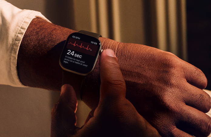 A person presses and holds the Digital Crown on Apple Watch Series 11 to measure heart health in ECG app