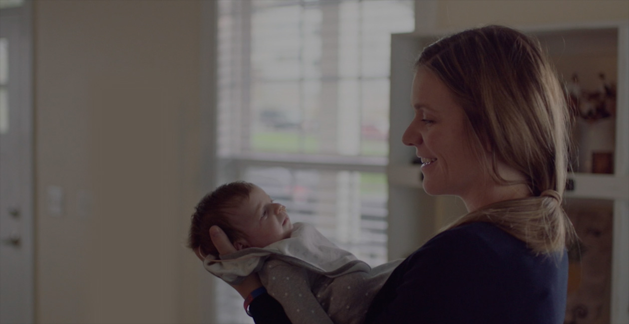 En mor smiler til sin nyfødte baby.